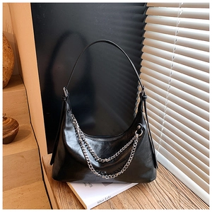 Detail view of black hobo bag with double silver chain straps on a wooden table