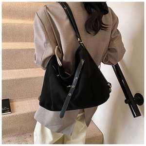 Detail of high-quality black tote bag with gold hardware buckles and slim shoulder strap