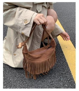Dettaglio borsa a tracolla in pelle scamosciata marrone con frange e perline in legno decor