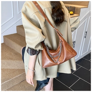Detail of brown vintage crossbody bag with glossy finish and silver chain accessory