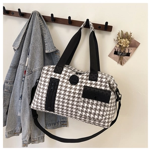 Detail of houndstooth travel bag with black logo patch and functional side pocket
