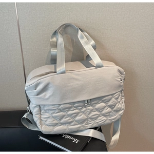 Detail of light grey travel bag with diamond quilted pattern and adjustable strap