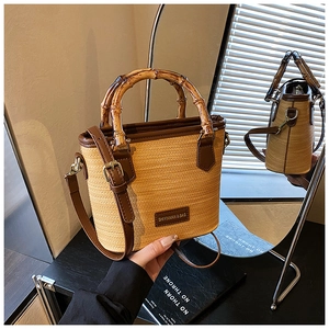 Detail of woven straw tote bag with bamboo handle and leather branding on a mirror