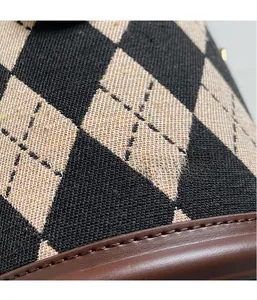 Detail of quilted canvas bucket bag with brown leather trim and precision stitching