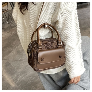 Detail of vintage brown leather handbag with floral patterns and front flap pocket