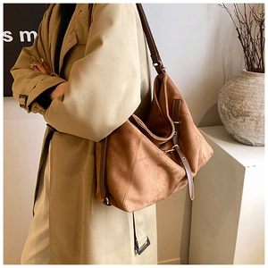 Detail of caramel suede tote bag with adjustable leather strap and brass metal hardware