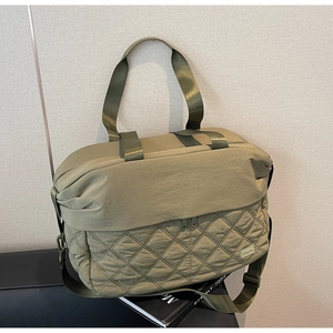 Macro detail of olive green quilted travel bag with premium nylon texture and handle