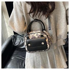 Detail of bohemian patterned crossbody bag with black leather handle on a model