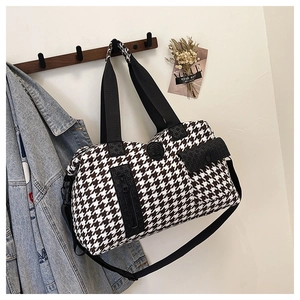 Detail of houndstooth travel bag showing side zipper pocket and adjustable shoulder strap