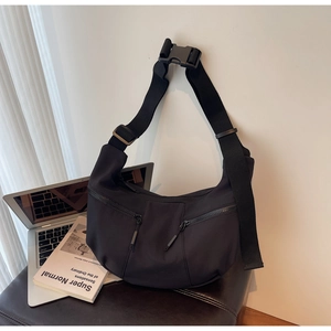 Detail of black nylon dumpling bag featuring dual zip pockets and tactical strap buckle