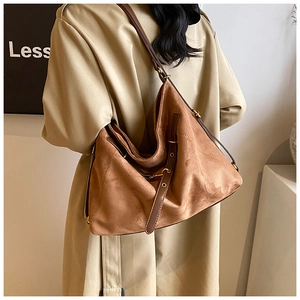 Detail of adjustable metal buckle and suede texture on large brown tote bag
