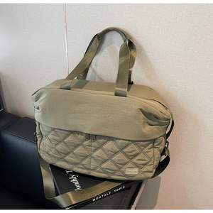 Detail of khaki travel bag with quilted diamond pattern and adjustable shoulder strap