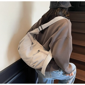 Detailed side view of a light grey nylon dumpling hobo bag with multiple functional pockets