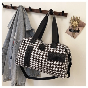 Close-up of a large houndstooth travel bag hanging on a wooden rack in a lifestyle setting