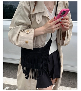 Détail d'un sac bandoulière noir en daim givré avec de longues franges bohèmes