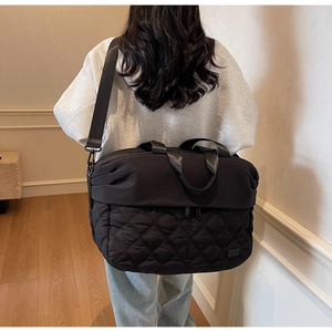 Macro detail of black quilted travel bag with dual handles and water-resistant fabric