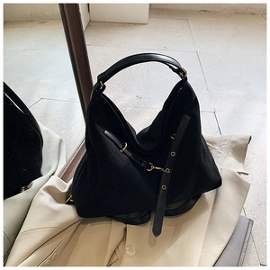 Detail of black canvas tote bag with leather handles and gold metal hardware accents