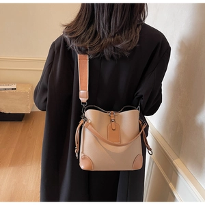 Detail of lychee pattern bucket bag with wide strap worn by a model in black coat