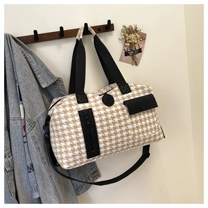 Detail of houndstooth travel bag with front pocket, logo patch and carry handles