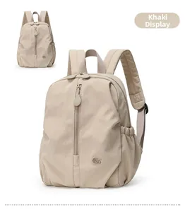 Detail view of khaki nylon backpack featuring front vertical zipper and elastic side pockets