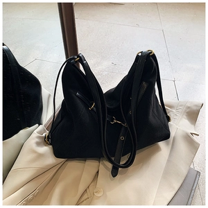 Detail view of black matte tote bag with gold hardware and shoulder strap on mirror