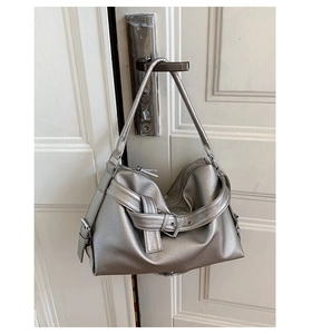 Close-up of silver pebble-grain hobo bag with metal buckle and wide shoulder strap