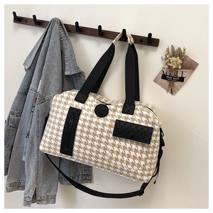 Close-up of houndstooth travel bag with zipper pockets and logo on a wooden hanger