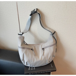 Detail view of a gray dumpling crossbody bag with adjustable strap and multiple pockets