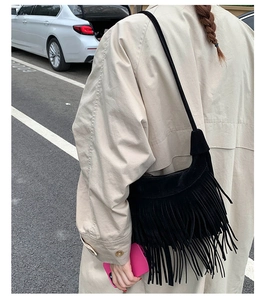 Détail d'un sac à bandoulière noir effet daim avec de longues franges sur un mannequin