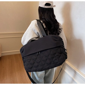 Detail of black quilted travel bag with adjustable strap worn by model in lifestyle setting