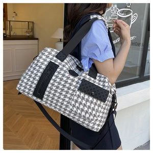 Detail of houndstooth travel bag showing side zipper pockets and durable woven canvas texture