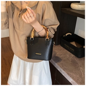 Detail of black woven bucket bag featuring vintage bamboo handle and gold logo hardware