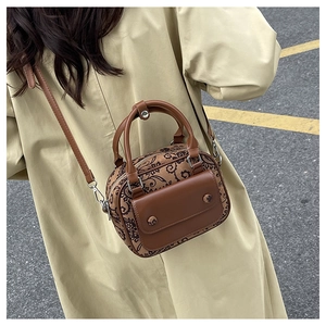Detailed close-up of a vintage brown crossbody bag with floral patterns on a trench coat