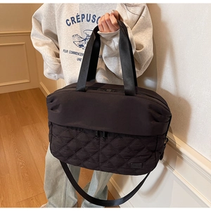 Detail of black large travel bag showing quilted diamond pattern and reinforced stitching