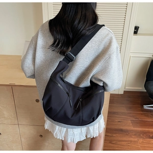 Detail view of black dumpling crossbody bag featuring multi-pocket zipper and wide strap