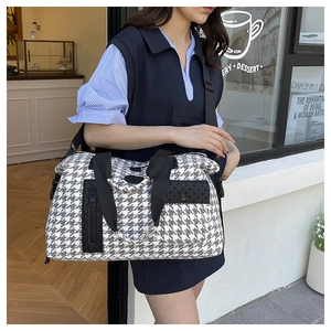 Detail of houndstooth travel bag with adjustable strap and front pocket storage