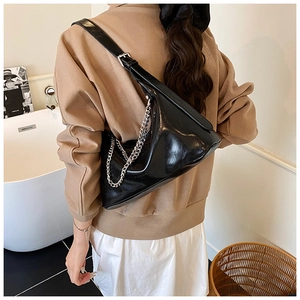 Close-up of black glossy shoulder bag with silver chain strap and sleek zipper detail