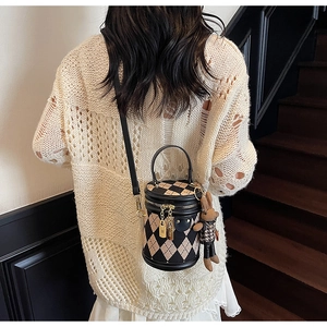 Detail of retro quilted cylinder bag with bunny charm worn by model on stairs