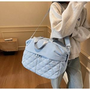 Detail of light blue quilted travel bag showing large capacity and quilted texture