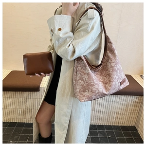Detail view of the floral hobo bag and brown clutch set worn with a light trench coat