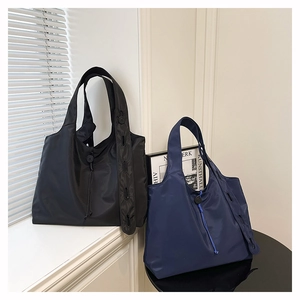 Detail of nylon tote bags in black and navy blue with drawstring and decorative straps