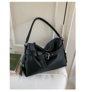 Detailed view of black lychee grain faux leather tote with decorative metal buckle straps