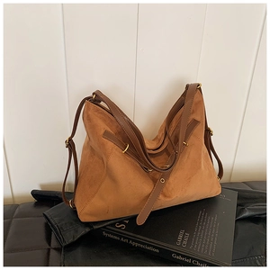 Detail of caramel brown matte suede tote bag with leather straps and gold buckle accents
