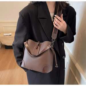 Detail of brown litchi pattern bucket bag with white contrast stitching and wide strap