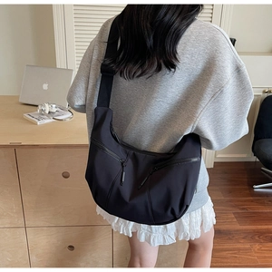 Detail of black nylon dumpling bag featuring dual zipper pockets and adjustable wide strap
