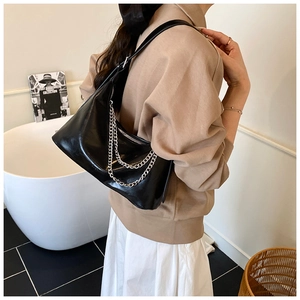 Detail of black glossy leather hobo bag with stylish double silver metal chain straps