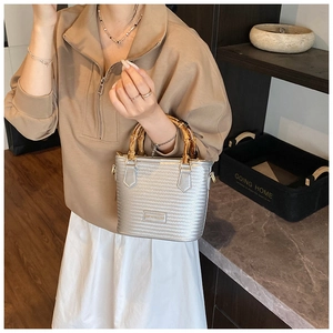 Detailed view of silver woven bucket bag featuring unique natural bamboo top handles