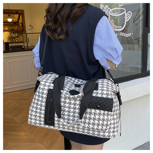 Detail of houndstooth travel bag showing multiple front pockets and woven textures