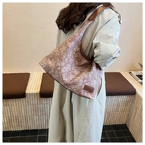 Close-up of pink floral tote bag with brown leather trim and rectangular logo detail