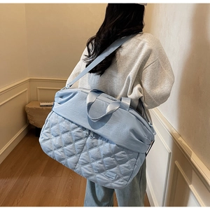 Macro view of light blue quilted travel bag showing waterproof nylon fabric and logo